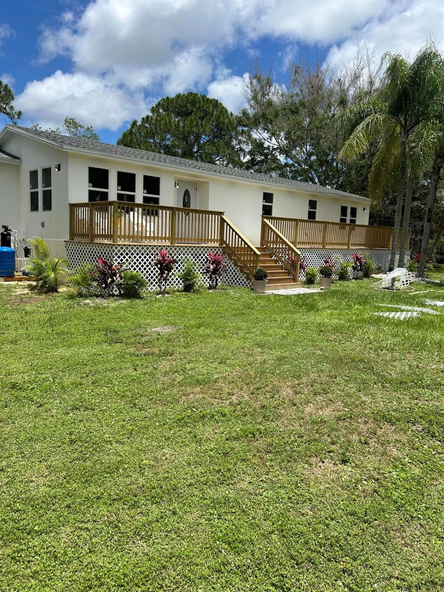 A white house features a large wooden deck with stairs and lattice skirting — 13555 150th Court N, Jupiter FL 33478, JUPITER, FL