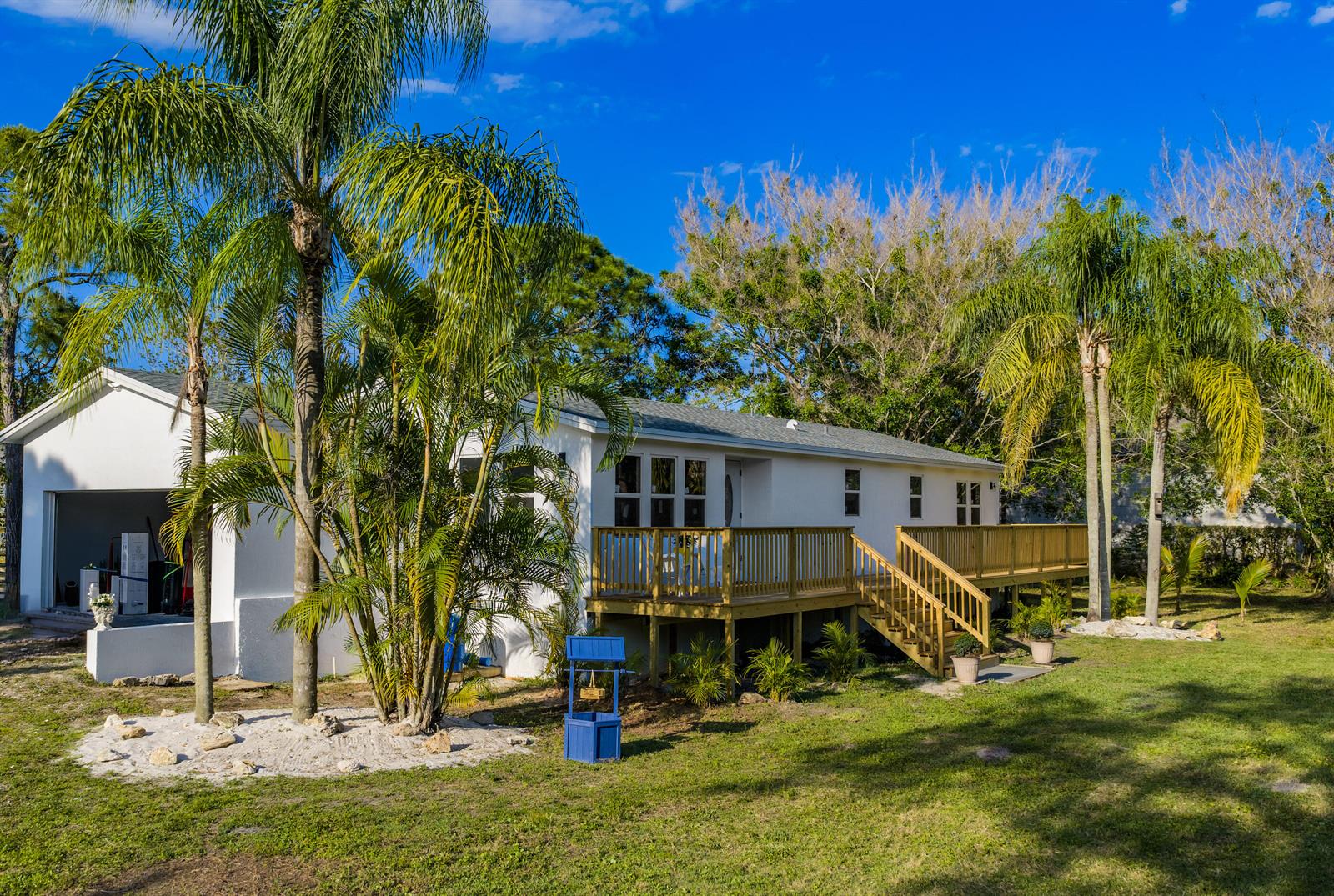A white house with a wooden deck and palm trees in a grassy yard — 13555 150th Court N, Jupiter FL 33478, JUPITER, FL