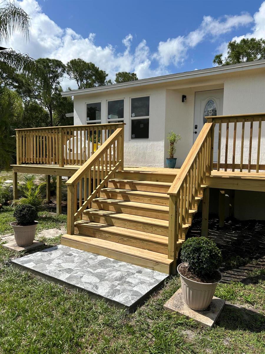 A newly constructed wooden deck with stairs leads to the front entrance of a house — 13555 150th Court N, Jupiter FL 33478, JUPITER, FL