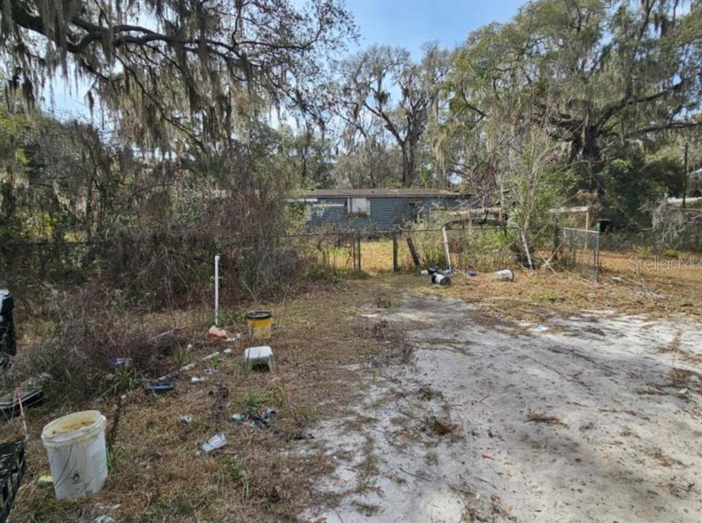 A weathered mobile home sits behind a chain-link fence on a dirt lot with debris — 4210 NE 175TH STREET ROAD, CITRA, FL