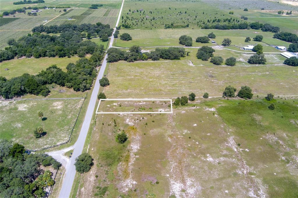 An aerial view shows a rectangular plot of land outlined in white beside a road — WHITE CLAY PIT ROAD, HAINES CITY, FL