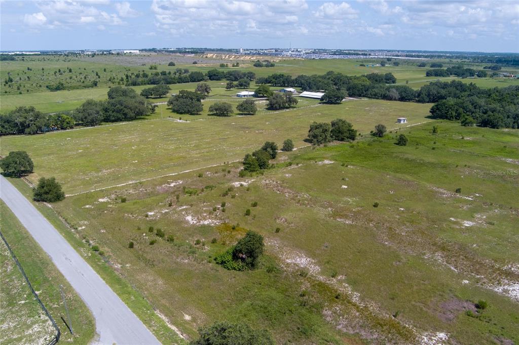 An aerial view shows a large, grassy, undeveloped plot of land bordered by a road — WHITE CLAY PIT ROAD, HAINES CITY, FL