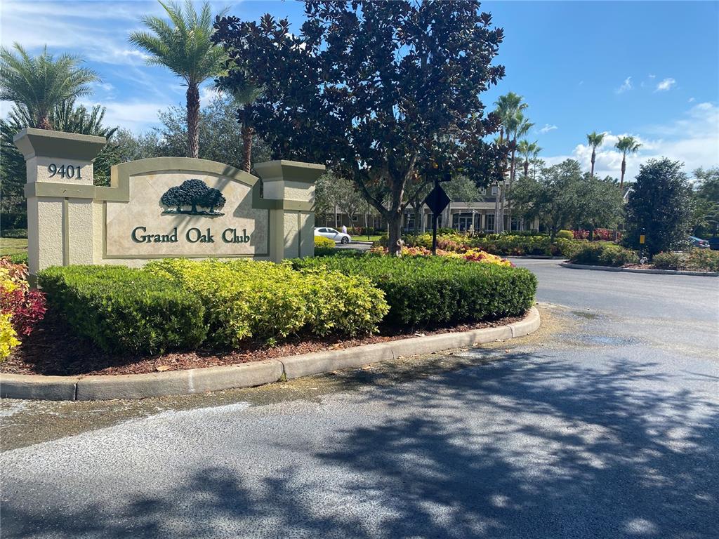 A stone monument sign for Grand Oak Club stands in front of a landscaped entrance — 8961 IRON OAK AVENUE, TAMPA, FL