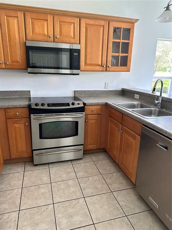 A kitchen features wood cabinets, stainless steel appliances, and tile flooring — 8961 IRON OAK AVENUE, TAMPA, FL