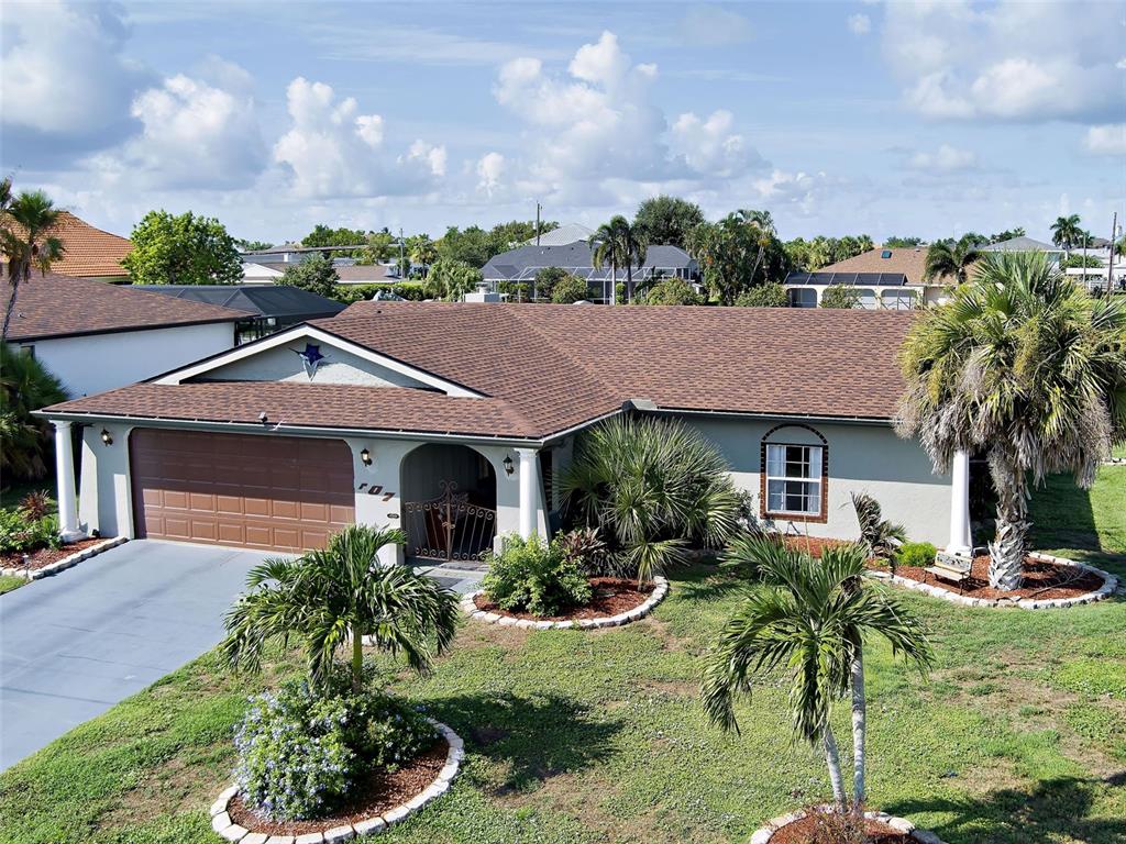 A single-story house with a brown shingled roof, a two-car garage, and a front lawn — 107 PECKHAM STREET SW, PORT CHARLOTTE, FL
