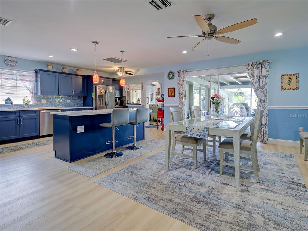 A kitchen and dining area featuring blue cabinets, a central island, and light wood flooring — 107 PECKHAM STREET SW, PORT CHARLOTTE, FL