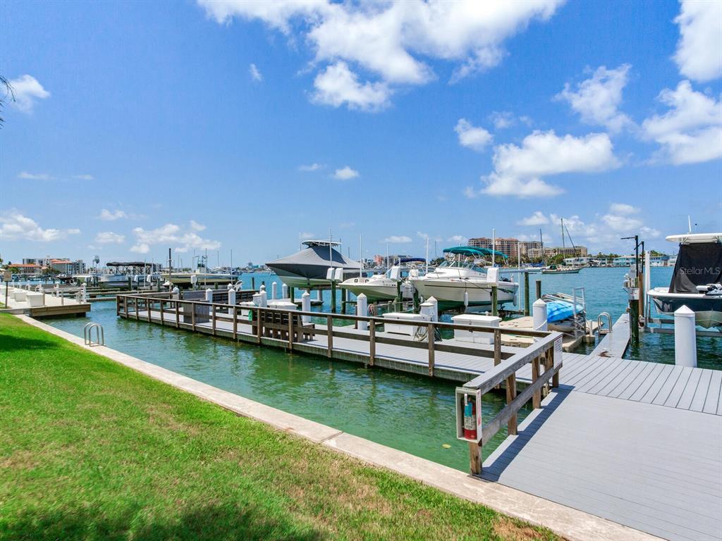 A wooden boat dock extends into a bay with several moored boats under a sky — 660 ISLAND WAY UNIT 202, CLEARWATER BEACH, FL
