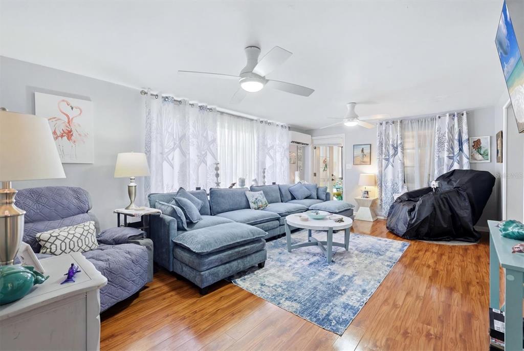 A living room features a blue sectional sofa, two ceiling fans, and wood-look flooring — 1006 42ND AVENUE DRIVE E, ELLENTON, FL