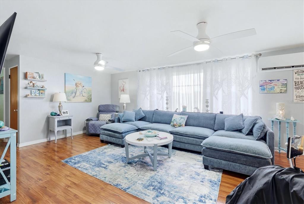 A living room features a blue sectional sofa, a round coffee table, and wood flooring — 1006 42ND AVENUE DRIVE E, ELLENTON, FL
