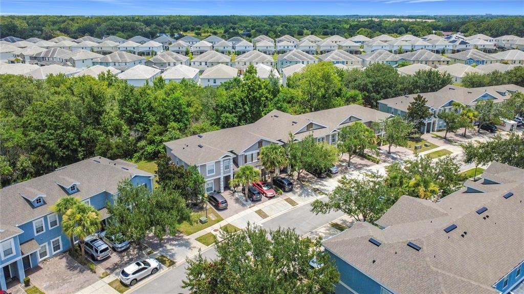 An aerial view shows multi-family townhomes with driveways and surrounding trees in a residential neighborhood — 2394 CARAVELLE CIRCLE, KISSIMMEE, FL