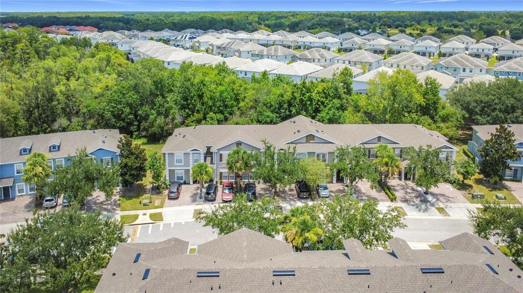 An aerial view shows a multi-unit townhouse complex with parking spaces and surrounding residential homes — 2394 CARAVELLE CIRCLE, KISSIMMEE, FL