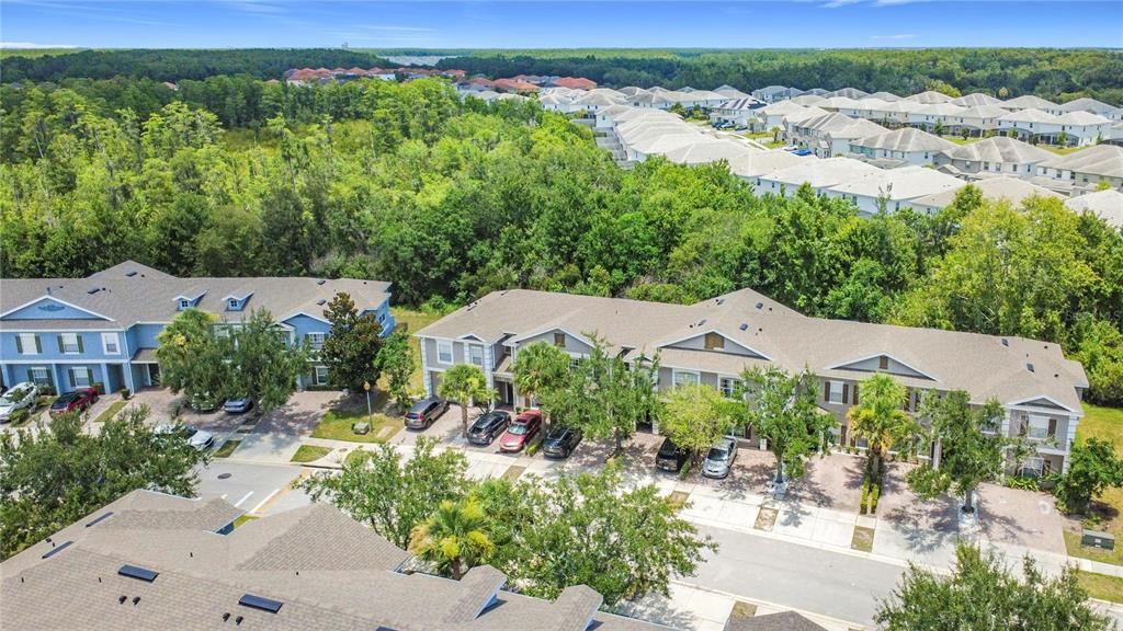 An aerial view shows several multi-story townhome buildings with driveways surrounded by trees and landscaping — 2394 CARAVELLE CIRCLE, KISSIMMEE, FL