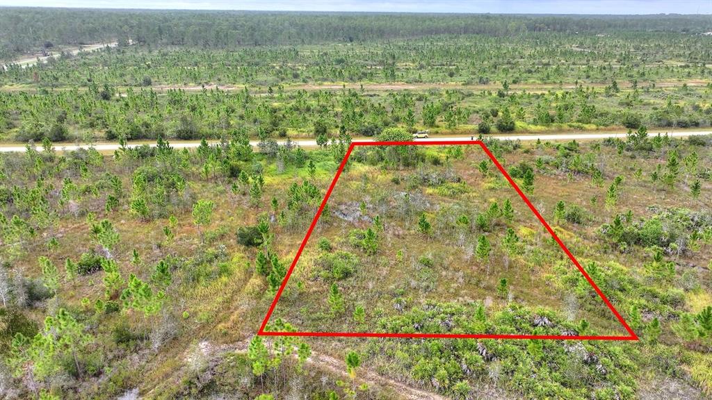 An aerial view of a vacant, grassy lot outlined in red next to a road — ALTHEA DRIVE, INDIAN LAKE ESTATES, FL