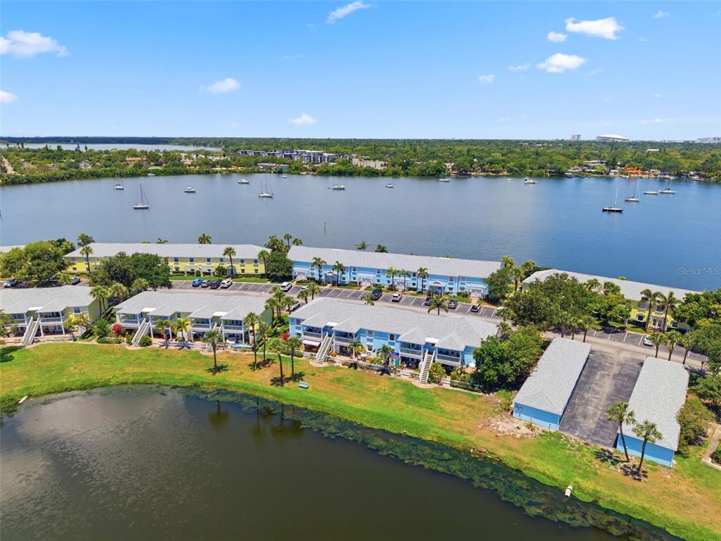 An aerial view shows apartment buildings with blue siding situated along a lake with boats — 144-166 POMPANO DRIVE SE UNIT A, ST PETERSBURG, FL
