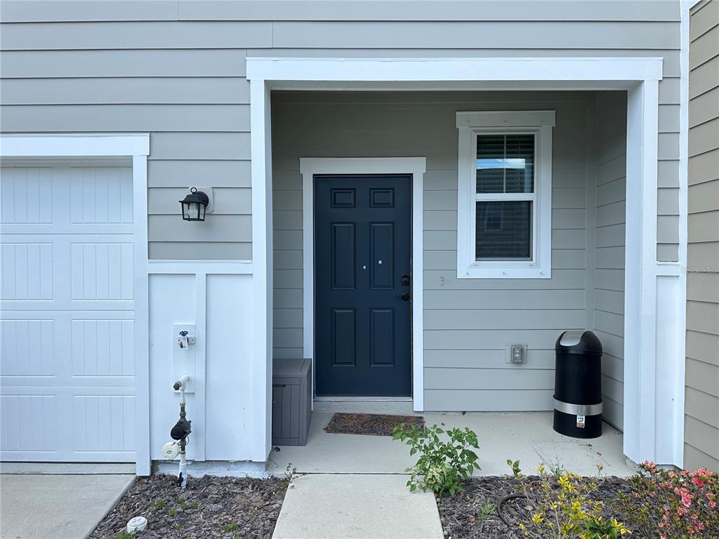 The exterior of a home features a dark blue front door, gray siding, and a garage — 6287 BUCKET COURT, GIBSONTON, FL