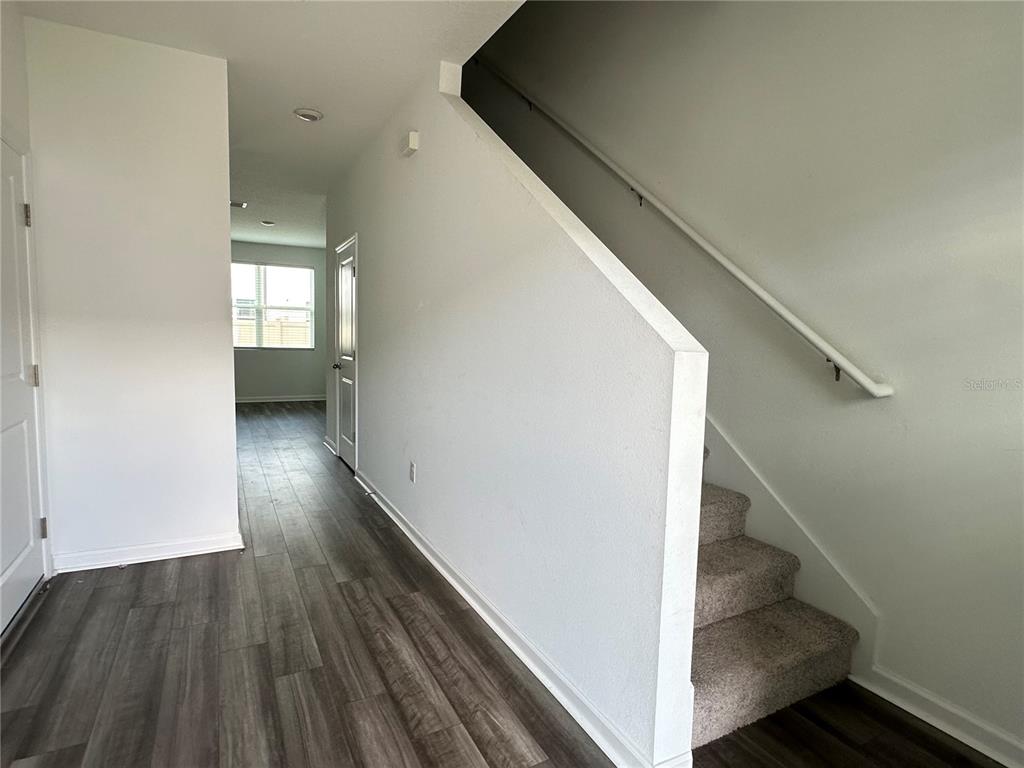 An entryway features wood-look flooring, a carpeted staircase with a handrail, and white walls — 6287 BUCKET COURT, GIBSONTON, FL