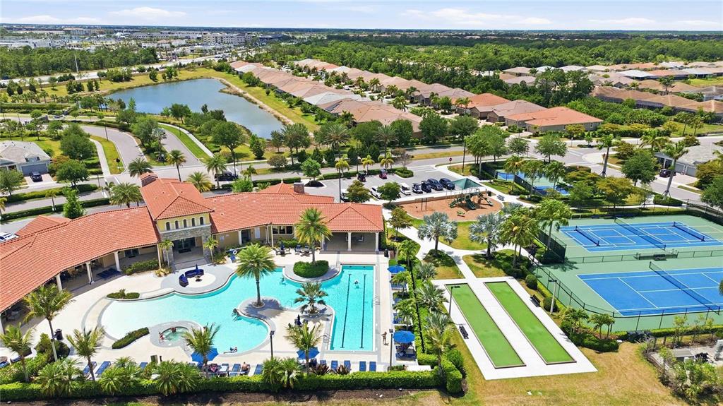 An aerial view shows a community clubhouse with a swimming pool and tennis courts — 11516 RENAISSANCE BOULEVARD, VENICE, FL