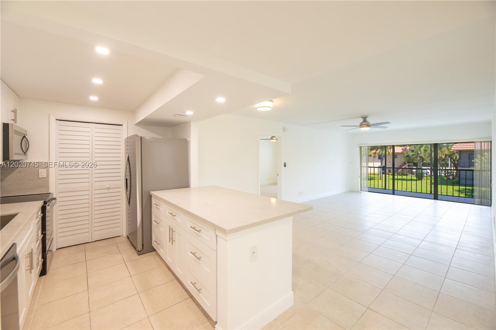A kitchen with white cabinets and a center island opens into a bright living area — 200 LAKEVIEW DR # 211, Weston FL 33326, WESTON, FL