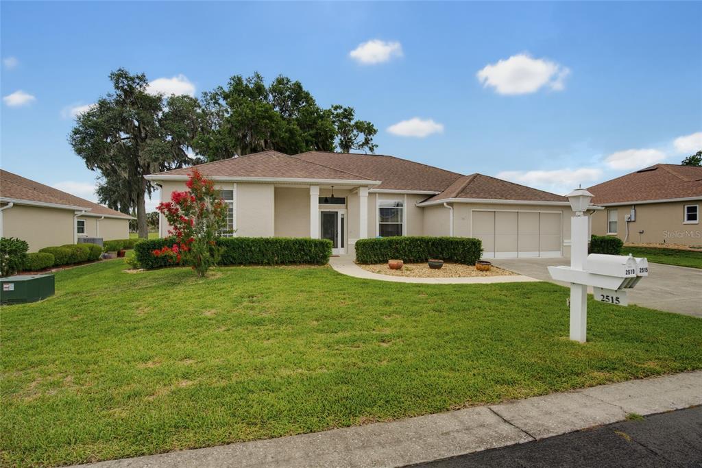 A single-story house with a tan exterior, a two-car garage, and a landscaped front yard — 2515 NW 53RD AVENUE ROAD, OCALA, FL