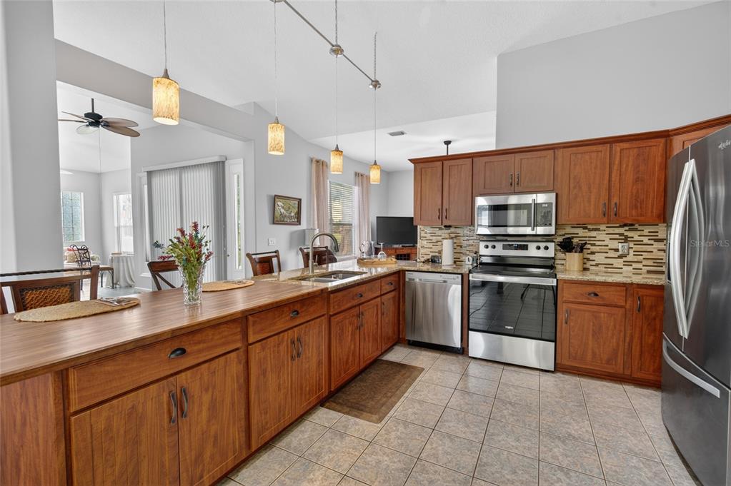 A kitchen features wood cabinets, stainless steel appliances, a large island, and tile flooring — 2515 NW 53RD AVENUE ROAD, OCALA, FL