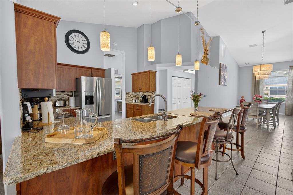 A kitchen features granite countertops, wood cabinetry, and a breakfast bar with bar stools — 2515 NW 53RD AVENUE ROAD, OCALA, FL