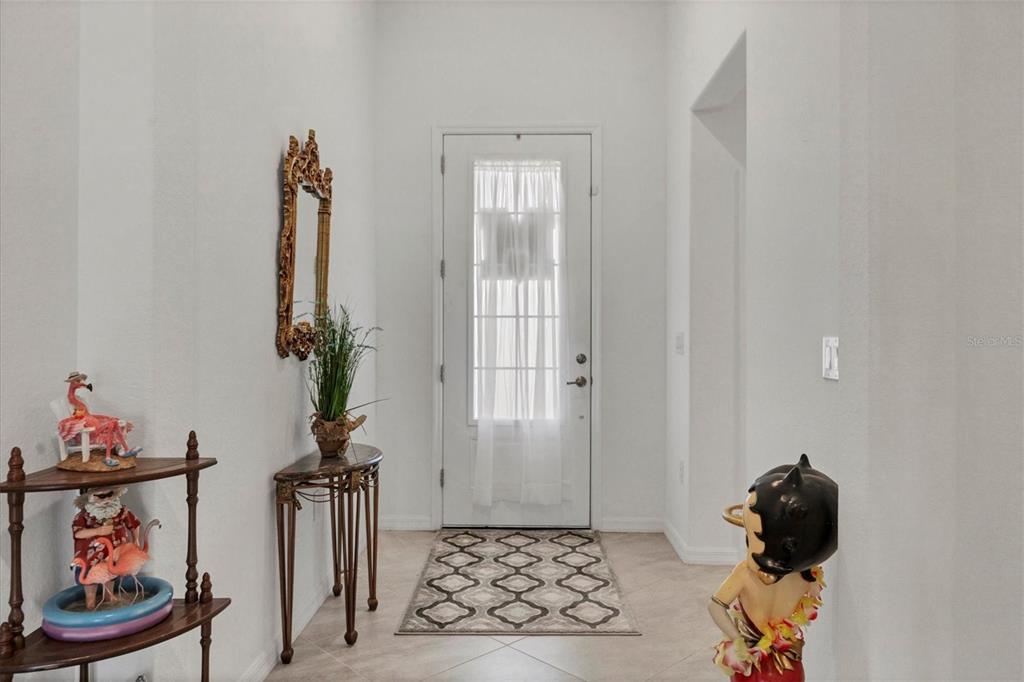 A bright entryway features a white front door, tiled floors, and decorative figurines — 14589 PONCE DE LEON TRAIL, PORT CHARLOTTE, FL