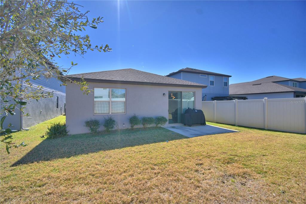 The exterior of a single-story house features a concrete patio and a vinyl privacy fence — 3589 ROCK CREEK LANE, KISSIMMEE, FL