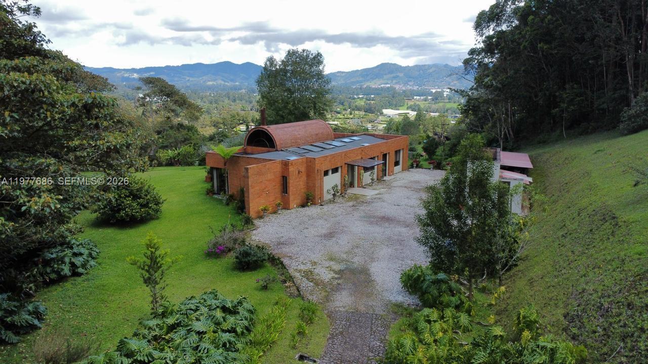 An aerial view of a modern brick house with a barrel-vaulted roof on a hillside — 183 Parcelacion El Yarumo, 055010, FL
