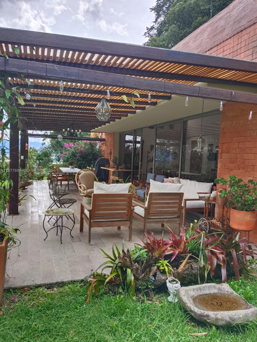 A covered outdoor patio features wooden furniture, a pergola, and a view of the landscape — 183 Parcelacion El Yarumo, 055010, FL