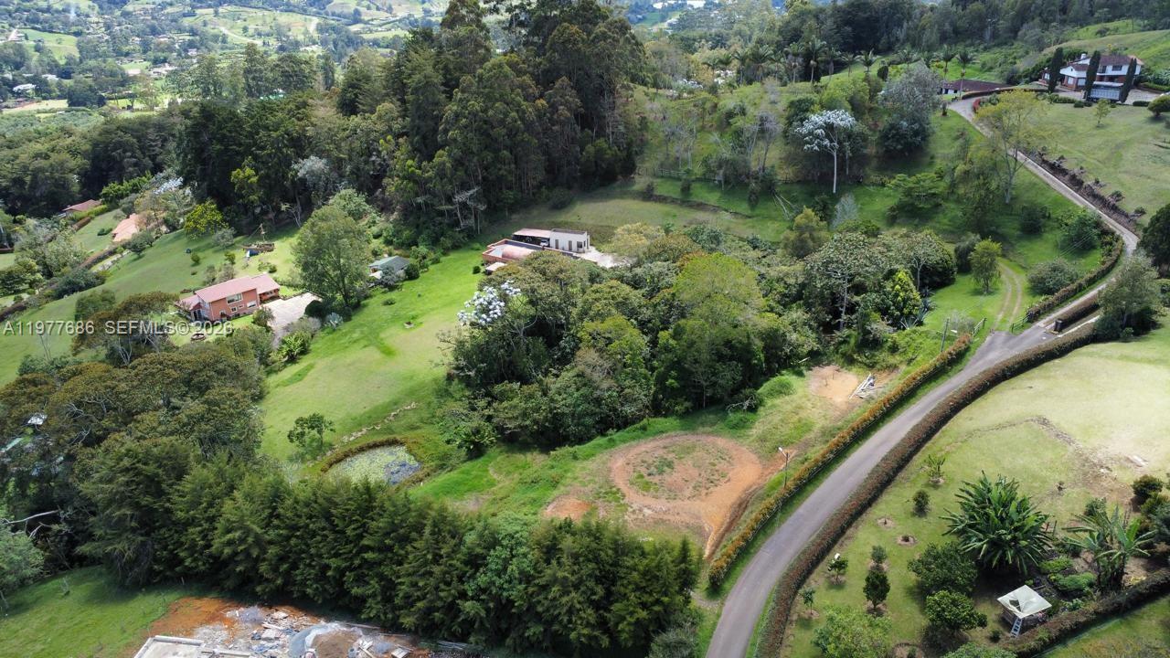 An aerial view shows a rural property with a house, trees, and a winding road — 183 Parcelacion El Yarumo, 055010, FL