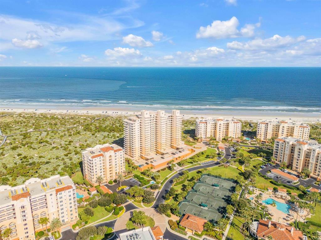 An aerial view shows several high-rise residential buildings near a sandy beach and ocean — 257 MINORCA BEACH WAY UNIT 406, NEW SMYRNA BEACH, FL