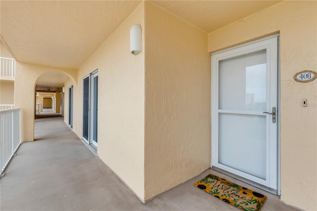 An exterior hallway with a white door labeled 406 and a welcome mat — 257 MINORCA BEACH WAY UNIT 406, NEW SMYRNA BEACH, FL