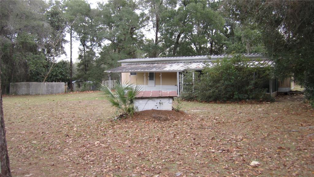 A single-story mobile home sits on a wooded lot with a small concrete well structure — 6973 N CARL G ROSE HWY, HERNANDO, FL