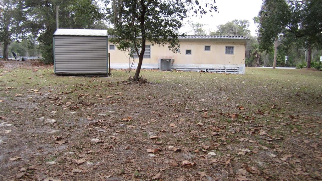 A single-story mobile home sits on a grassy lot next to a metal storage shed — 6973 N CARL G ROSE HWY, HERNANDO, FL