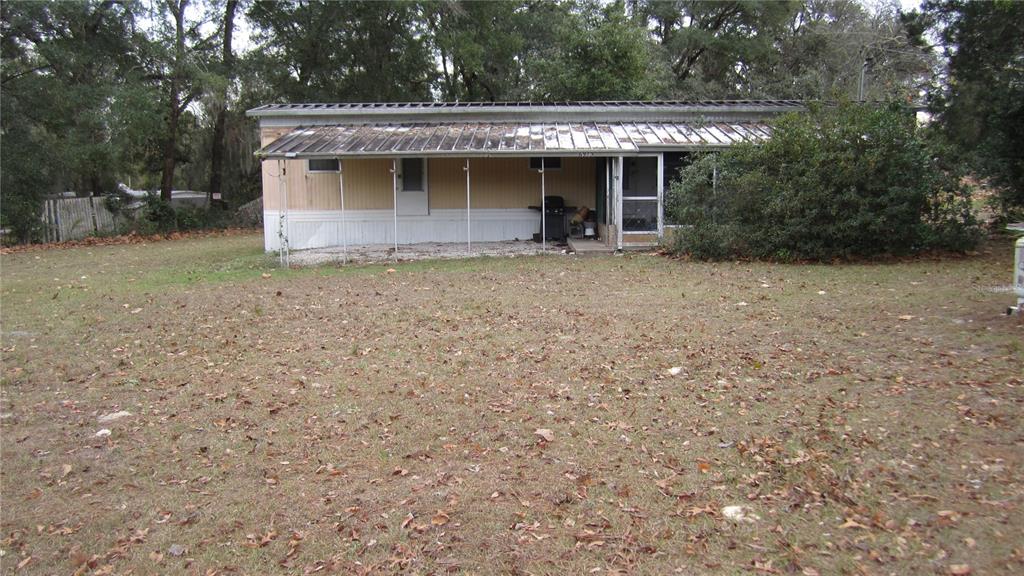 A single-story mobile home features a metal roof, a covered porch, and a grassy yard — 6973 N CARL G ROSE HWY, HERNANDO, FL