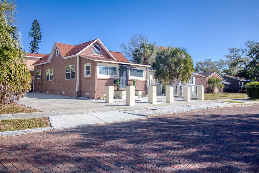 A single-story house with a reddish-brown exterior and a red roof sits on a brick street — 675 16TH AVENUE S UNIT 1, ST PETERSBURG, FL
