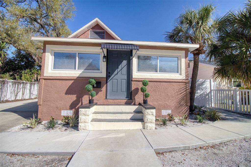 A tan stucco house with a gray front door, white trim, and a small front porch — 675 16TH AVENUE S UNIT 1, ST PETERSBURG, FL
