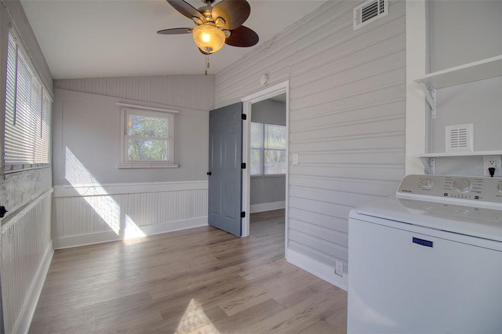 A laundry room features light gray walls, wood-look flooring, a ceiling fan, and a washing machine — 675 16TH AVENUE S UNIT 1, ST PETERSBURG, FL