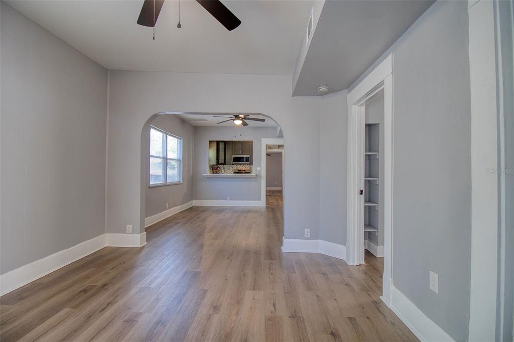 A living room with light gray walls, wood-look flooring, and an arched entryway to the kitchen — 675 16TH AVENUE S UNIT 1, ST PETERSBURG, FL