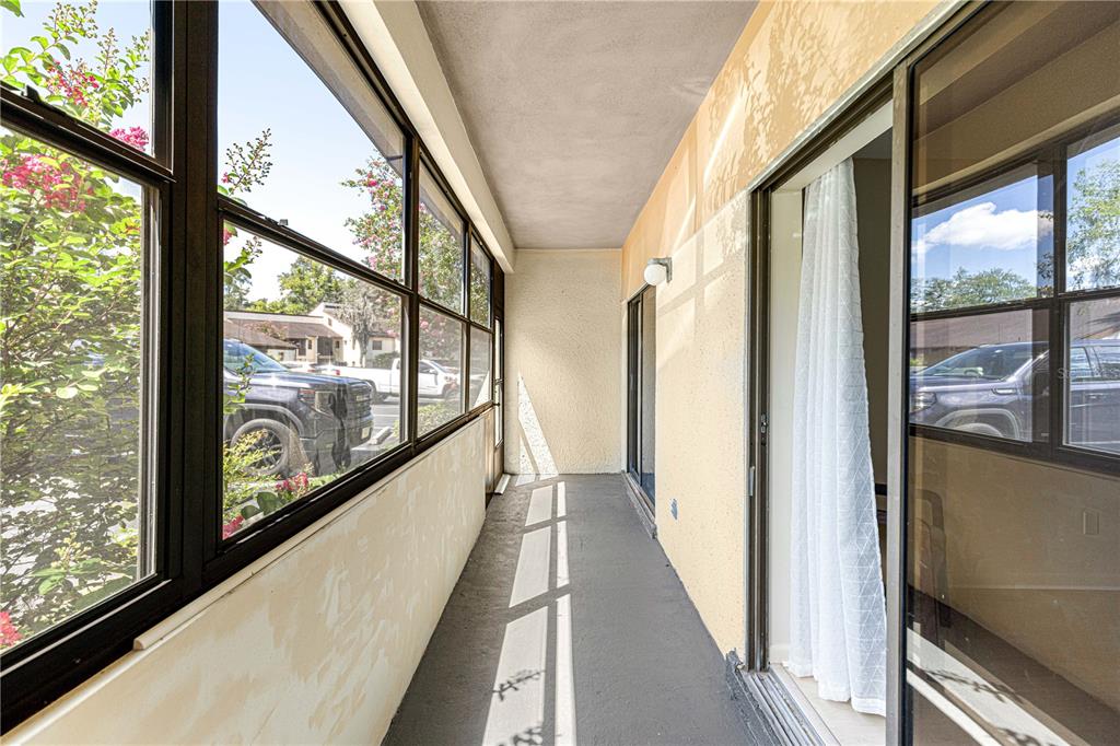A narrow, covered balcony features gray flooring, large windows, and a sliding glass door — 3507 E FORT KING STREET UNIT 129, OCALA, FL
