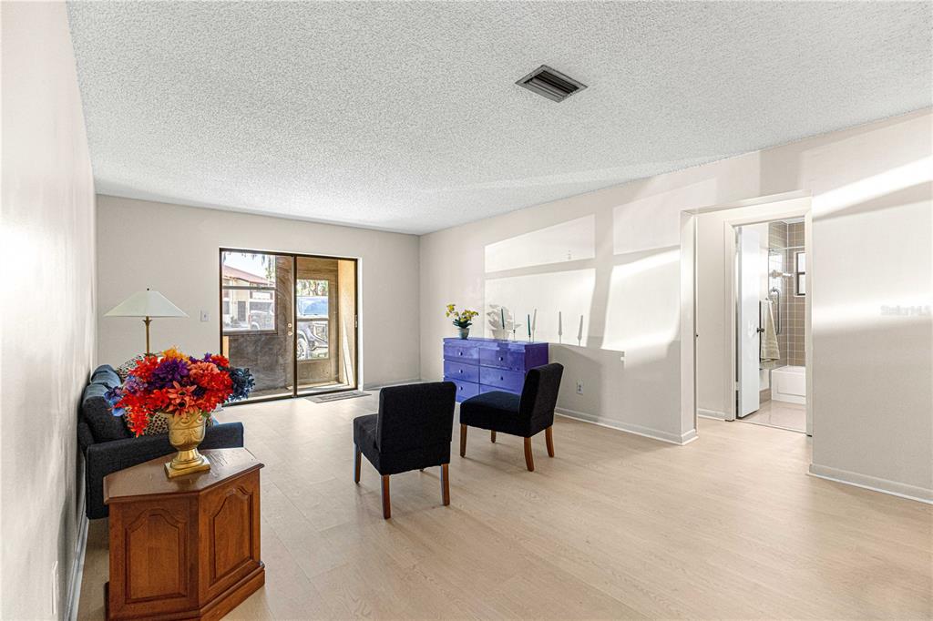 A living room with light wood floors, a blue dresser, two chairs, and a sofa — 3507 E FORT KING STREET UNIT 129, OCALA, FL