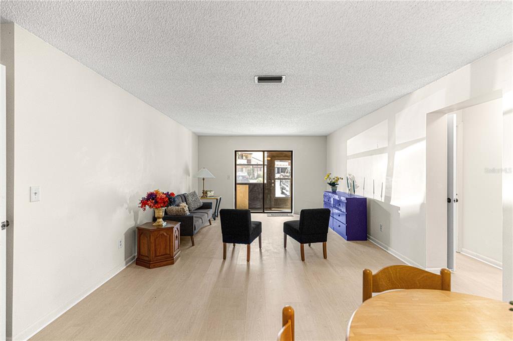 A living room features light wood-look flooring, white walls, two black chairs, and a sofa — 3507 E FORT KING STREET UNIT 129, OCALA, FL
