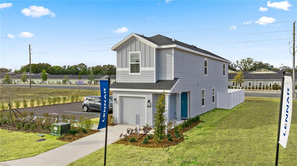 A two-story gray house with a single-car garage stands on a grassy lot — 9199 SW 91ST COURT, OCALA, FL