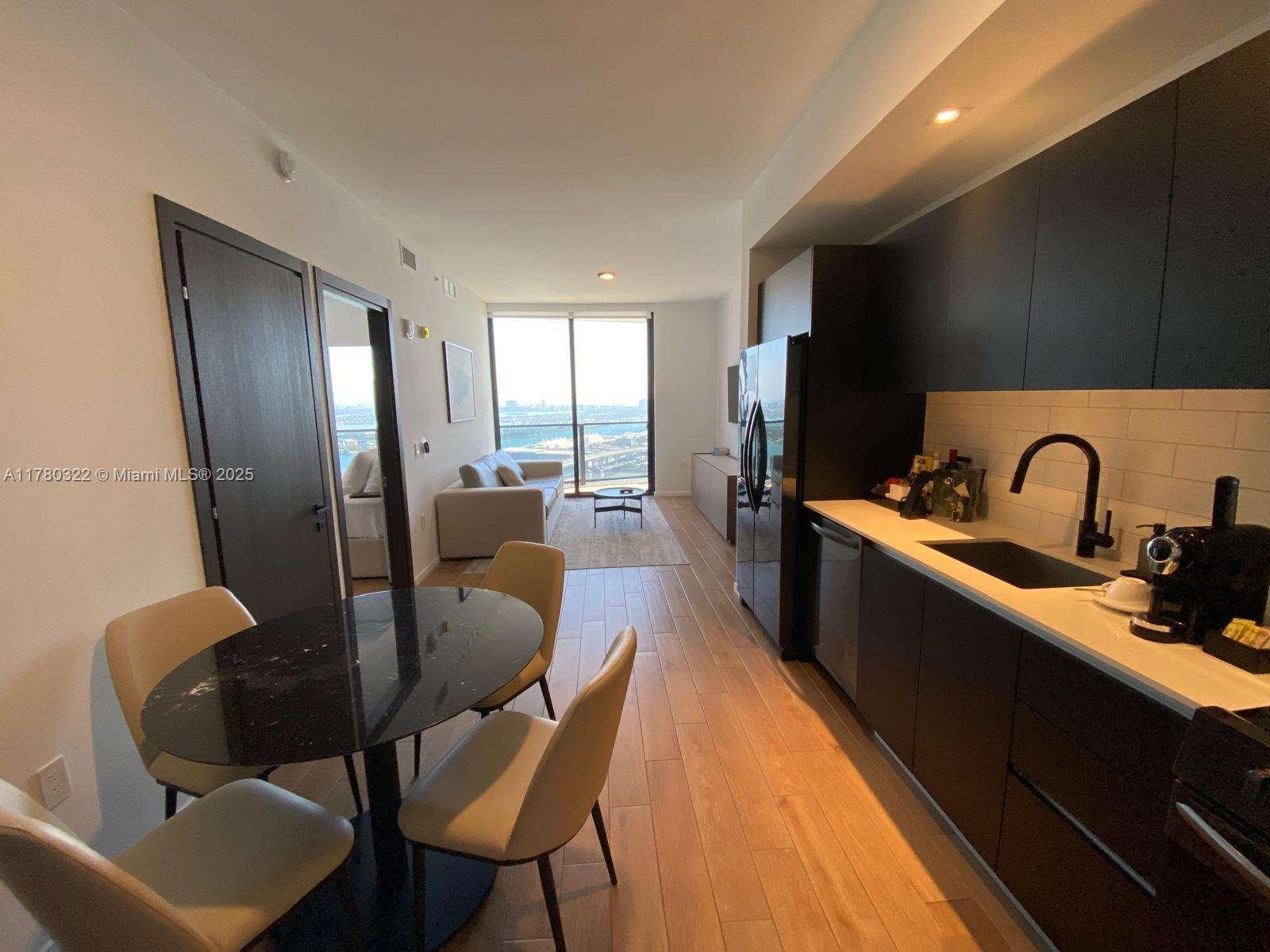 An open-concept apartment features a kitchen with dark cabinetry, a dining area, and a living room — 398 NE 5th St # 2910, Miami FL 33132, MIAMI, FL