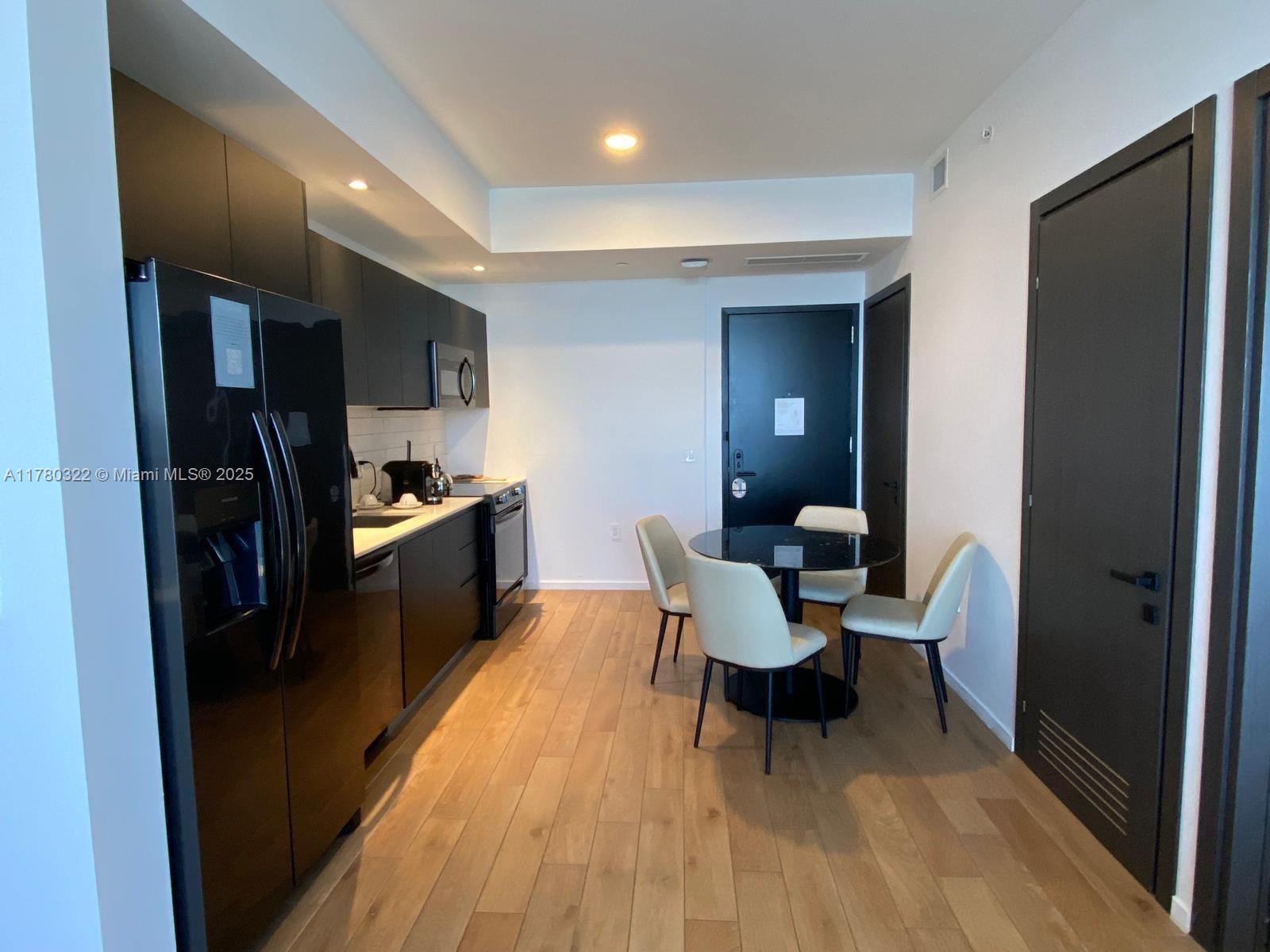 A kitchen and dining area feature dark cabinetry, stainless steel appliances, and light wood flooring — 398 NE 5th St # 2910, Miami FL 33132, MIAMI, FL