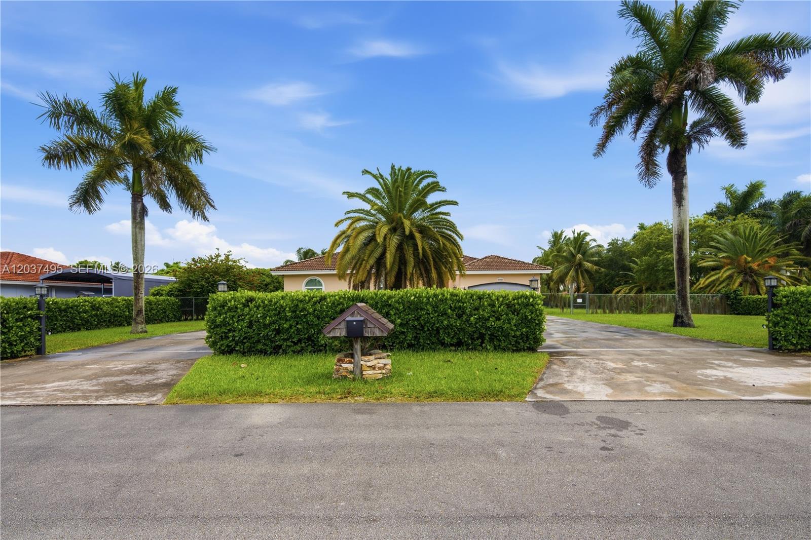 A house with a large hedge, palm trees, and a stone-based mailbox in the front yard — 16933 SW 215th Ter, Miami FL 33187, MIAMI, FL