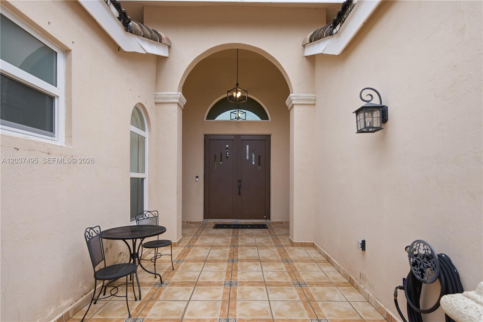 An outdoor entryway features a tiled floor, arched doorway, and double front doors — 16933 SW 215th Ter, Miami FL 33187, MIAMI, FL