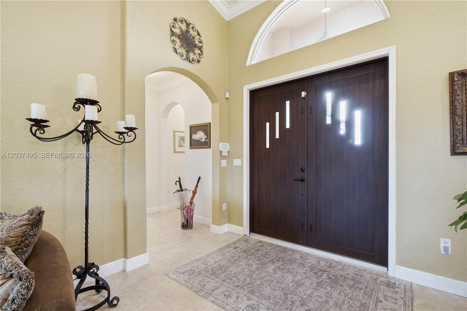 A foyer features a dark wood double door, arched entryway, and a tall candelabra — 16933 SW 215th Ter, Miami FL 33187, MIAMI, FL