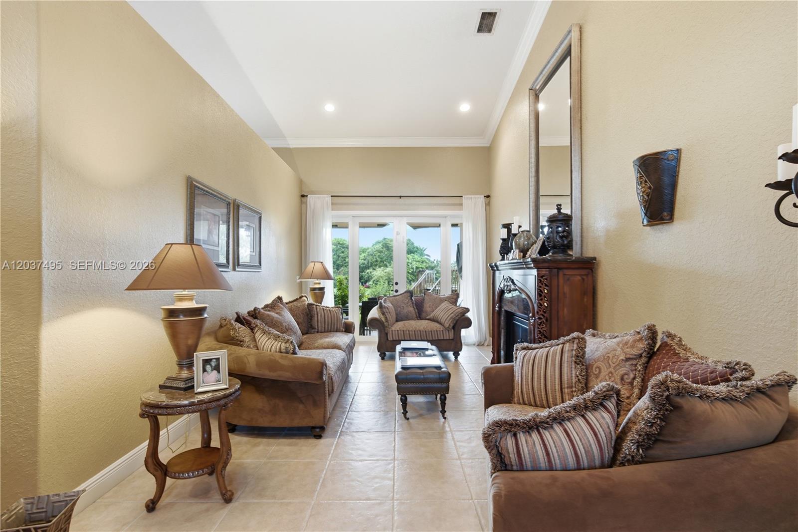A living room features tile floors, a fireplace, and glass doors leading to a patio — 16933 SW 215th Ter, Miami FL 33187, MIAMI, FL