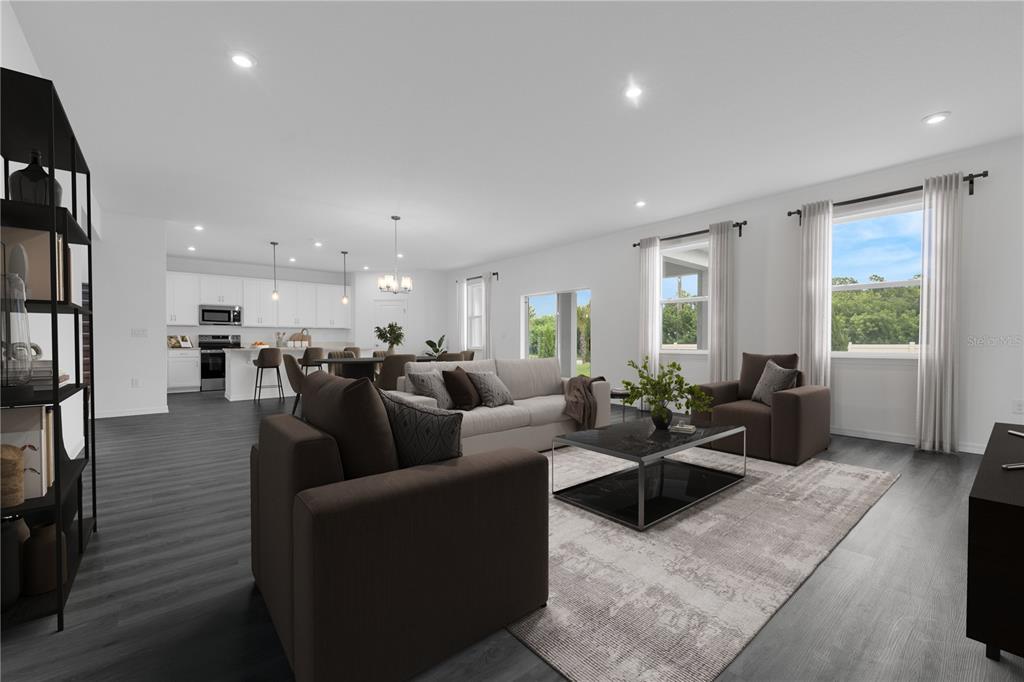 A bright, open-concept living room and kitchen featuring dark wood floors and neutral furniture — 1819 SHADOW BOX BEND, ST CLOUD, FL